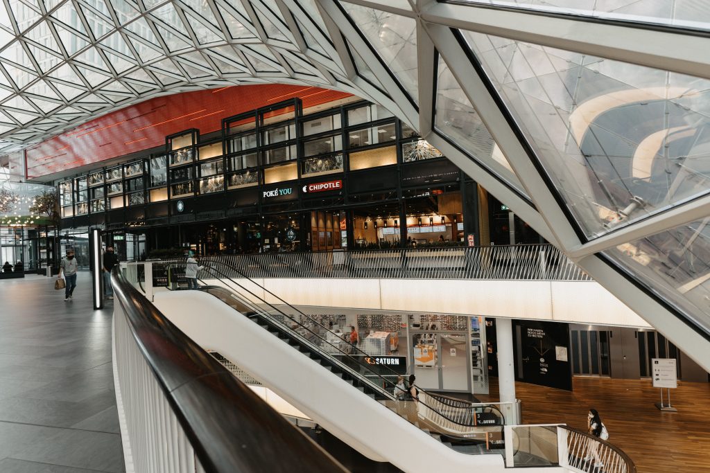Interior view of a modern shopping mall featuring a striking glass ceiling and multiple floors.